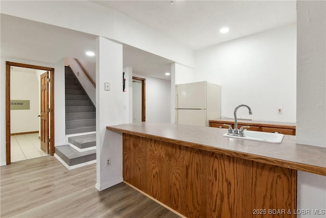 kitchen with sink, light hardwood / wood-style floors, and white refrigerator