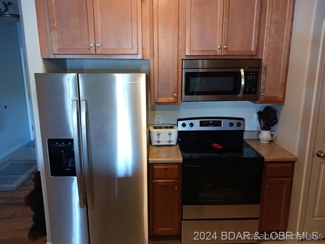 kitchen with appliances with stainless steel finishes, light countertops, and wood finished floors