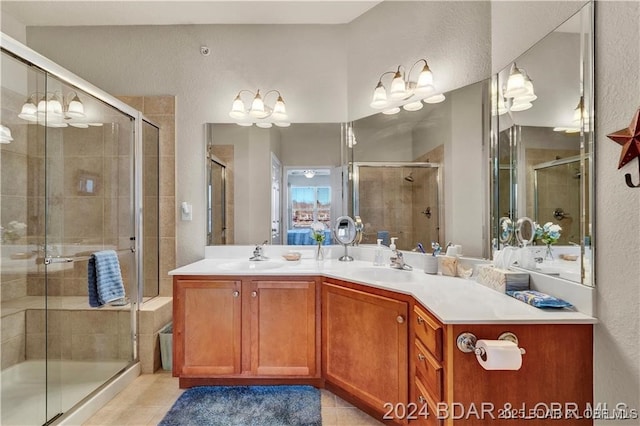 full bath with a stall shower, tile patterned flooring, double vanity, a textured wall, and a chandelier