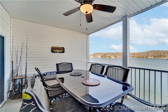 sunroom with ceiling fan, a water view, and outdoor dining space