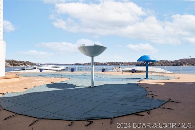 view of pool with a water view and a patio