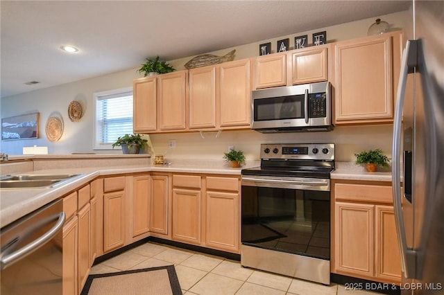 kitchen featuring light brown cabinetry, light tile patterned flooring, stainless steel appliances, and sink