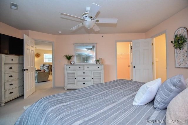 carpeted bedroom with a spacious closet, a closet, and ceiling fan