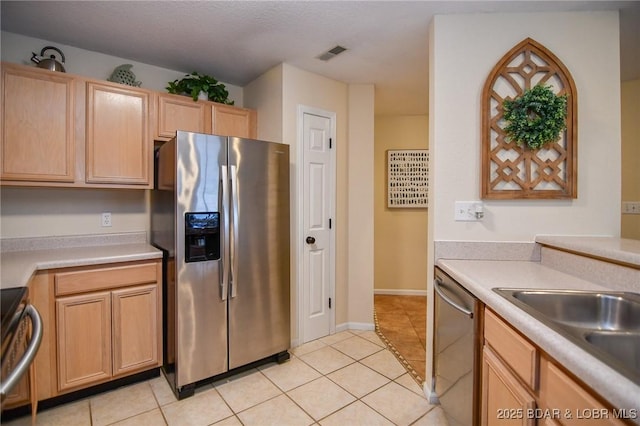 kitchen featuring light brown cabinetry, light tile patterned floors, stainless steel appliances, and sink