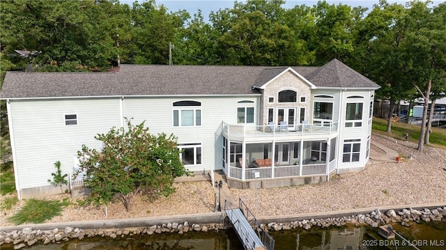 rear view of house featuring a sunroom, a balcony, and a water view