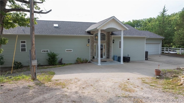 rear view of property featuring cooling unit and a garage