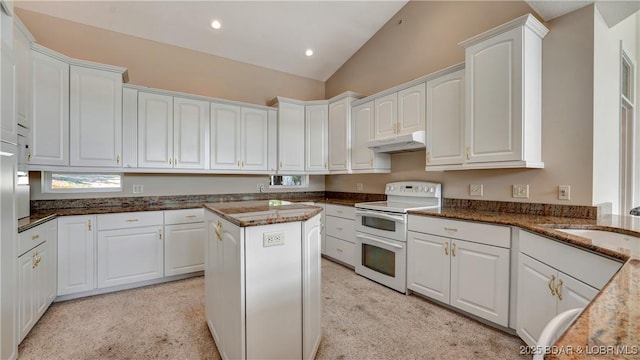 kitchen featuring electric range, white cabinets, dark stone counters, and vaulted ceiling