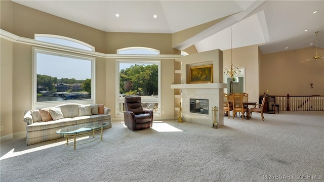 carpeted living room featuring a fireplace, a towering ceiling, and ceiling fan with notable chandelier