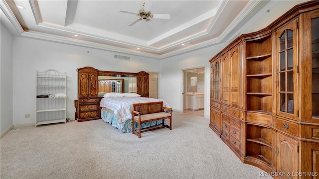 carpeted bedroom with ceiling fan, a raised ceiling, ensuite bathroom, and crown molding