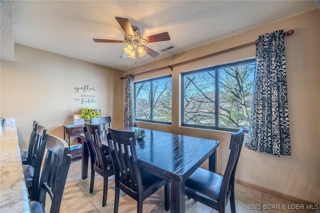 tiled dining area featuring ceiling fan and a textured ceiling