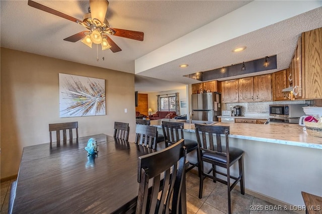 tiled dining area with ceiling fan and a textured ceiling