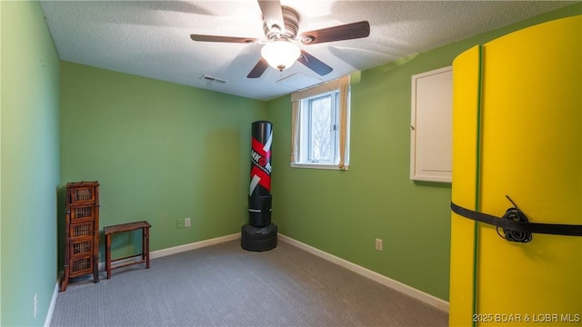 interior space with a textured ceiling, carpet floors, and ceiling fan