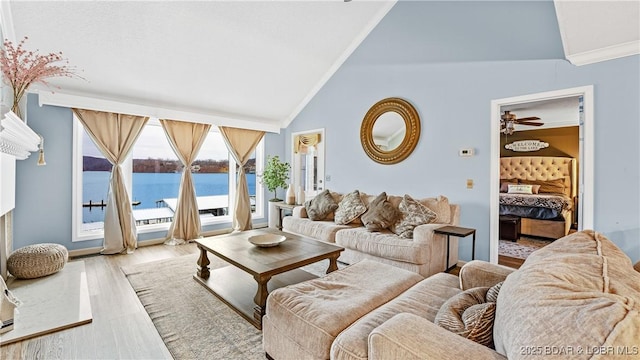 living room with a water view, vaulted ceiling, ornamental molding, and light hardwood / wood-style flooring