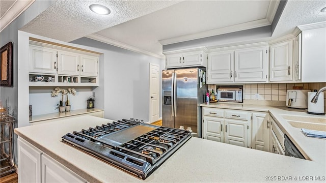 kitchen with white cabinetry, backsplash, a textured ceiling, appliances with stainless steel finishes, and ornamental molding