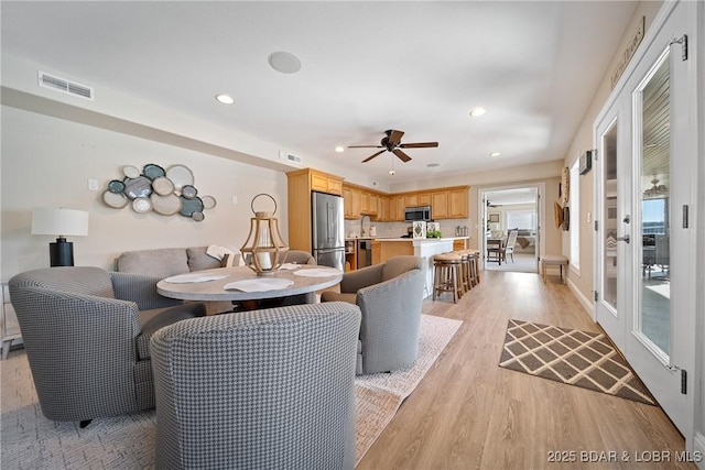 living area with visible vents, a ceiling fan, light wood-style floors, and recessed lighting