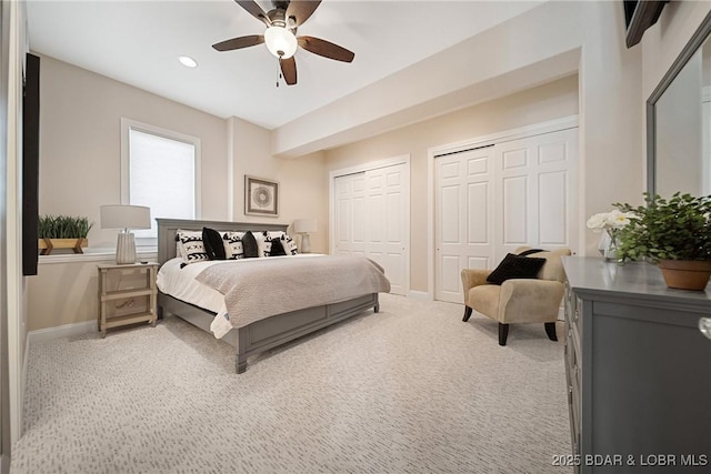 bedroom featuring ceiling fan, multiple closets, light carpet, and baseboards