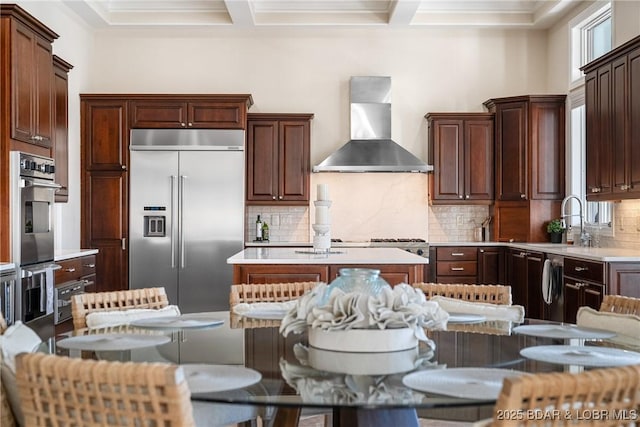 kitchen featuring stainless steel appliances, wall chimney range hood, backsplash, a sink, and crown molding