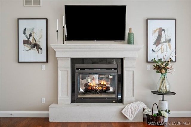 details featuring a fireplace, wood finished floors, visible vents, and baseboards