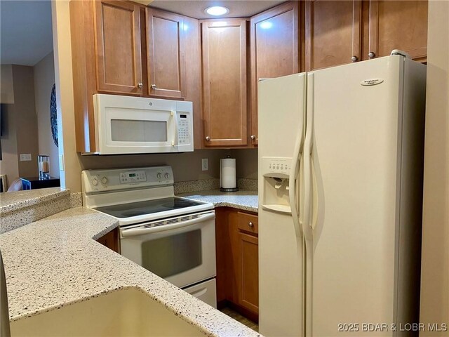 kitchen featuring white appliances and light stone counters