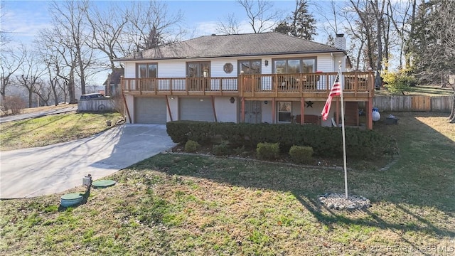 view of front facade with a front yard, a garage, and a wooden deck