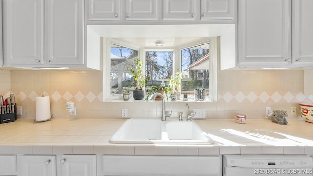 kitchen with white cabinets, dishwasher, decorative backsplash, and sink