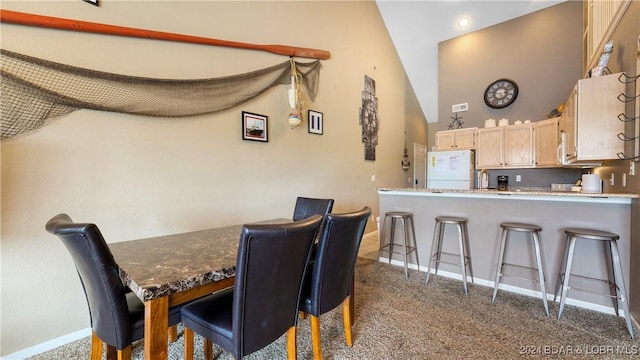 carpeted dining area with vaulted ceiling