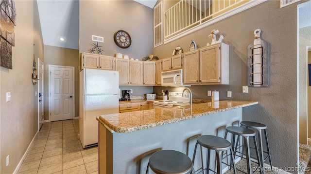 kitchen featuring kitchen peninsula, light brown cabinets, white appliances, and light tile patterned flooring