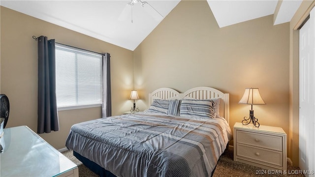 bedroom with ceiling fan, dark carpet, a closet, and vaulted ceiling