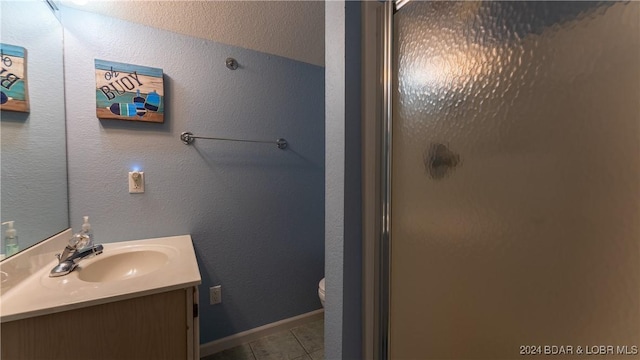 bathroom with toilet, tile patterned flooring, vanity, and walk in shower