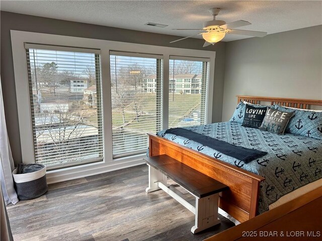 bedroom featuring wood-type flooring, a textured ceiling, and ceiling fan