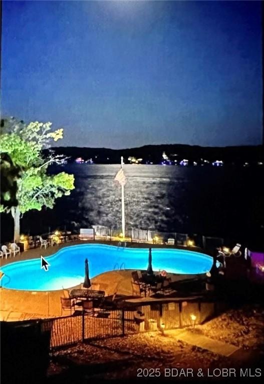 pool at twilight featuring a water view