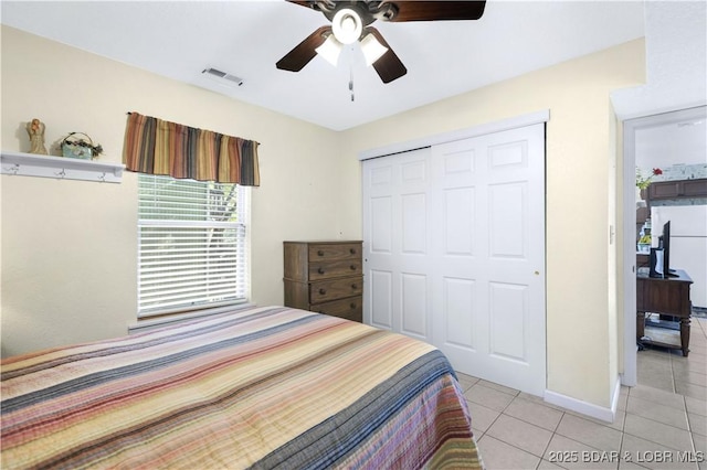 bedroom featuring white refrigerator, a closet, ceiling fan, and light tile patterned floors