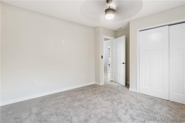 unfurnished bedroom with ceiling fan, light carpet, and a closet