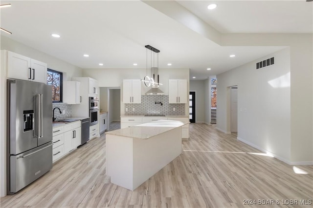 kitchen featuring white cabinets, appliances with stainless steel finishes, a center island, and light wood-type flooring