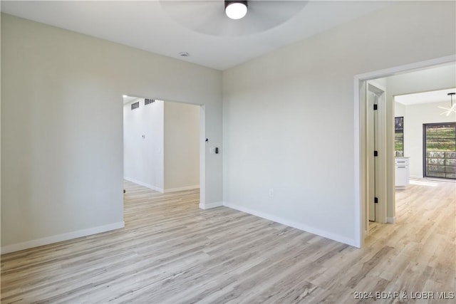 spare room featuring ceiling fan with notable chandelier and light hardwood / wood-style floors