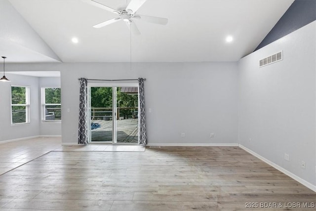 empty room with ceiling fan, light hardwood / wood-style floors, and vaulted ceiling