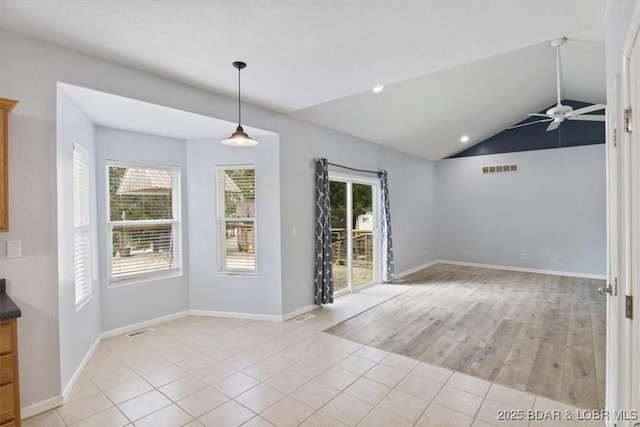 interior space featuring ceiling fan, light tile patterned flooring, a healthy amount of sunlight, and vaulted ceiling