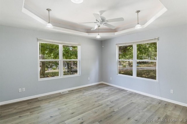 unfurnished room featuring ceiling fan, a raised ceiling, and plenty of natural light