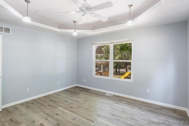 spare room featuring wood-type flooring, a tray ceiling, and ceiling fan