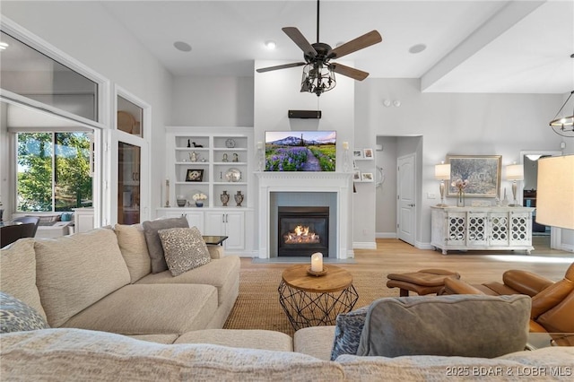 living room featuring ceiling fan, built in features, and light wood-type flooring