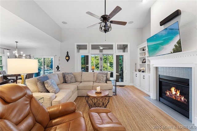 living room with a fireplace, ceiling fan with notable chandelier, and light wood-type flooring