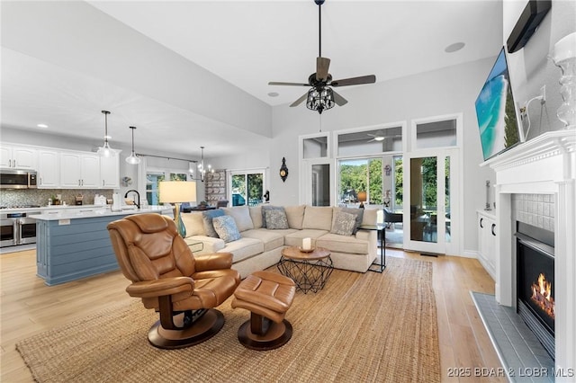 living room featuring ceiling fan with notable chandelier, light hardwood / wood-style floors, and sink