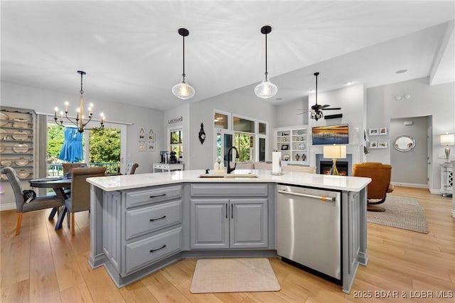 kitchen with dishwasher, sink, decorative light fixtures, a center island with sink, and ceiling fan with notable chandelier