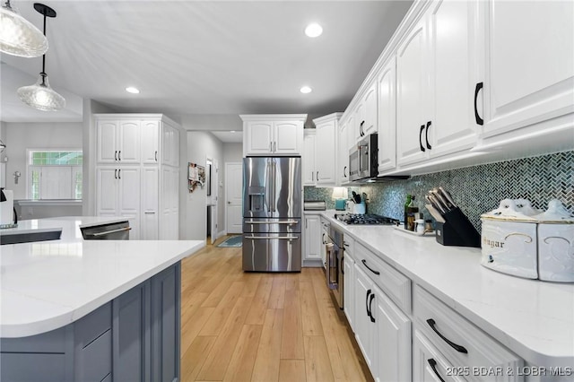 kitchen with decorative light fixtures, stainless steel appliances, and white cabinetry