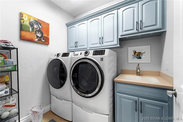 laundry area featuring washer and dryer, cabinets, and sink