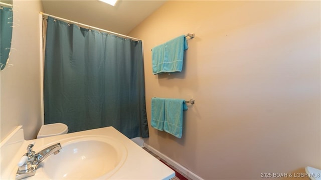 bathroom with toilet, vaulted ceiling, walk in shower, and sink