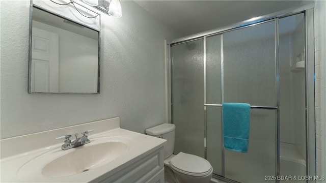 bathroom with vanity, toilet, and a shower with shower door