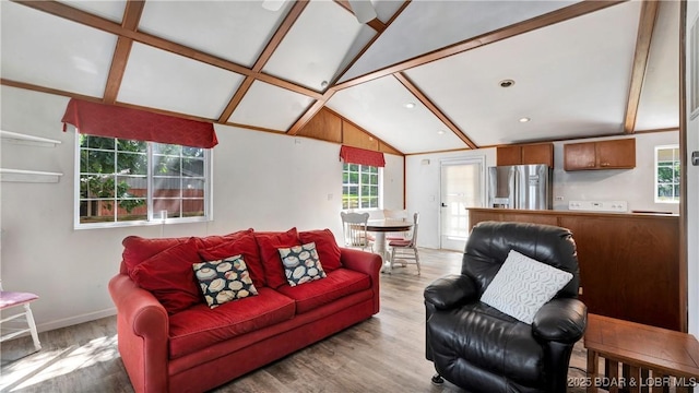 living room with vaulted ceiling with beams and light hardwood / wood-style flooring