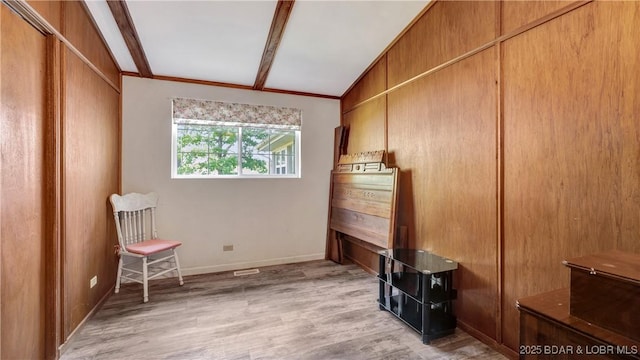 interior space featuring light wood-type flooring, lofted ceiling with beams, and crown molding