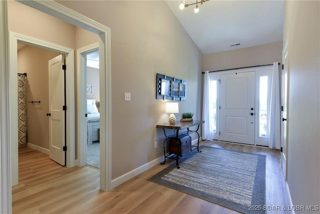 entrance foyer with a healthy amount of sunlight, light hardwood / wood-style floors, and vaulted ceiling